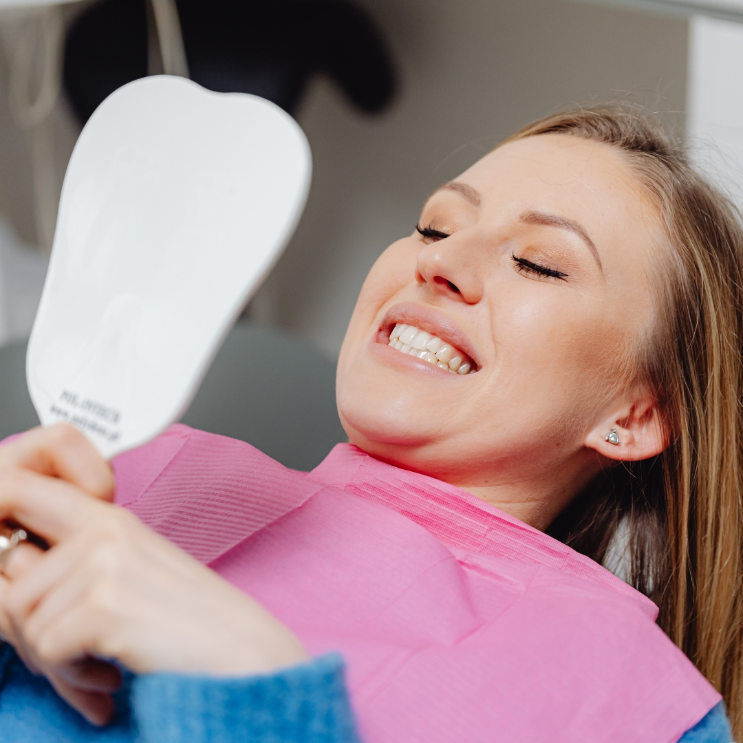 Patient smiling while checking teeth in a mirror after treatment