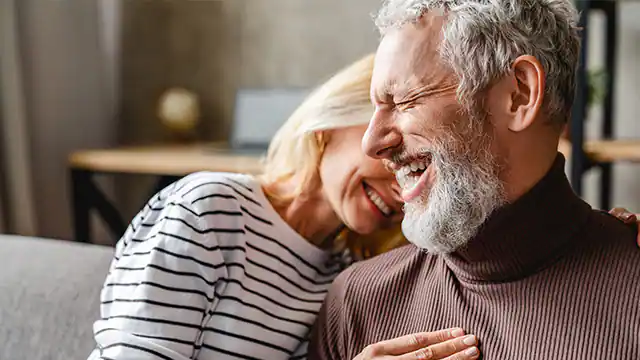 Happy older couple smiling after All-on-4 dental implant treatment